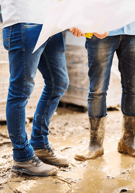 Image of peoples legs in work boots in the mud