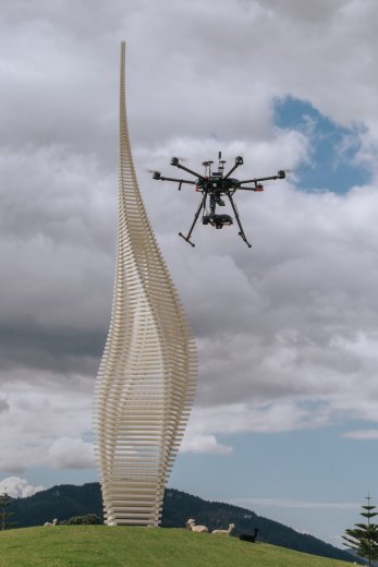 Drone in air next to sculpture