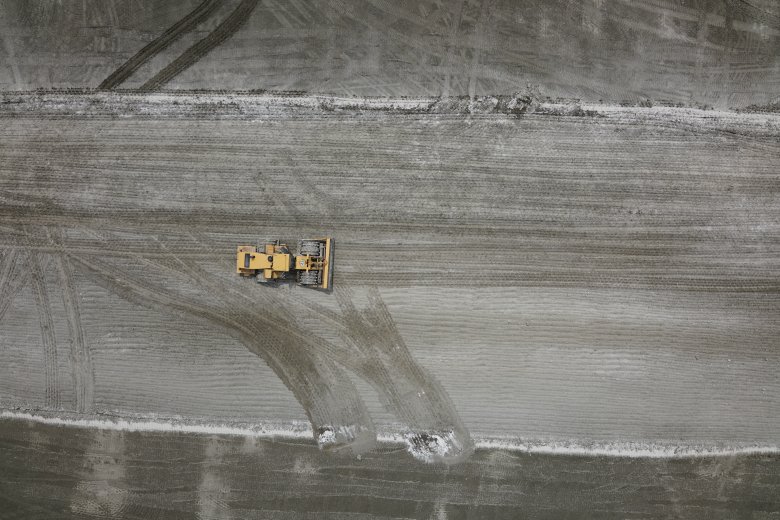 Aerial shot of grader on large dirt expanse